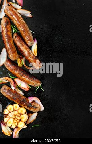 Saucisses grillées à l'oignon et à l'ail. Vue de dessus sur une plaque de barbecue en fer noir. Banque D'Images