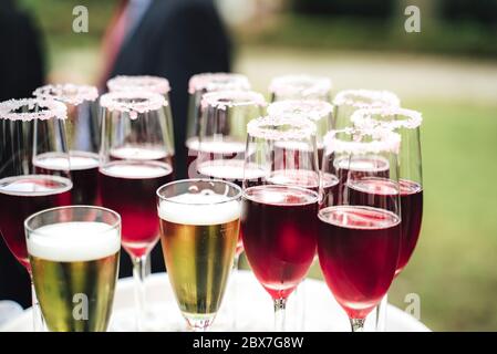 Plusieurs verres avec diverses boissons colorées. Boissons alcoolisées dans des verres dewy. Arrière-plan extérieur. Célébration, anniversaire, fête, mariage. Banque D'Images