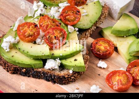 Toast à l'avocat avec tomates cerises grillées et feta. Banque D'Images