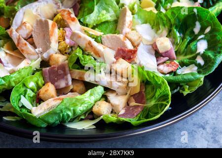 Salade césar au poulet sur une assiette noire. Banque D'Images
