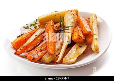 Légumes-racines rôtis dans un plat blanc, isolés. Banque D'Images