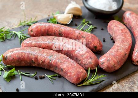 Saucisses crues sur ardoise, avec herbes et épices. Vue latérale. Banque D'Images