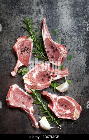 Côtelettes d'agneau crues aux herbes sur ardoise sombre. Vue du dessus. Banque D'Images