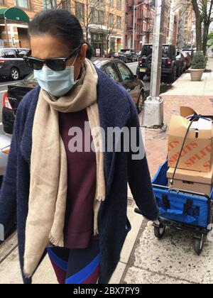 Femme de chambre avec masque de protection tirant chariot alimentaire, New York City, New York, États-Unis, avril 2020 Banque D'Images