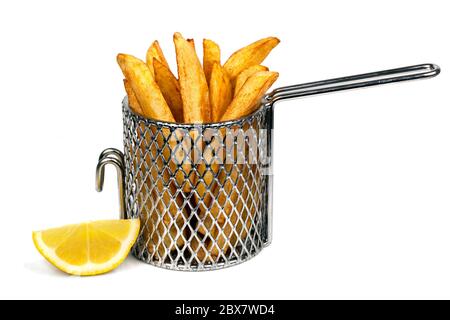 Frites ou chips de pommes de terre dans un petit panier de friture en fil métallique, isolé sur blanc. Avec coin citron. Banque D'Images