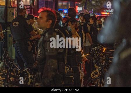 NEW YORK, NY - 03 JUIN : les manifestants à la main sont alignés et traitent avant d'être conduits dans un bus correctionnel sur les lieux d'une arrestation de masse de manifestants Banque D'Images