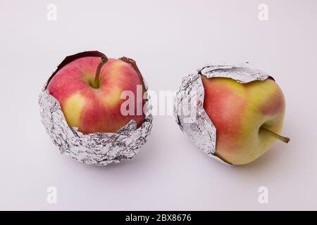 Plusieurs pommes mûres et juteuses rouges et jaunes, enveloppées dans du papier d'aluminium sur fond blanc Banque D'Images