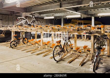 Parking vélo autonome sur plusieurs niveaux dans la ville de Tokyo, au Japon, la nuit, avec la plupart des casiers encore vides. Banque D'Images