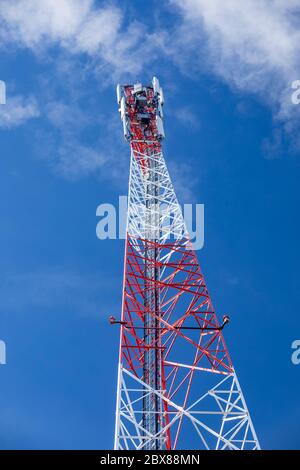 Sommet d'une tour d'antenne réseau cellulaire métallique rouge et blanc autosupport avec plusieurs antennes contre le ciel bleu , Finlande Banque D'Images