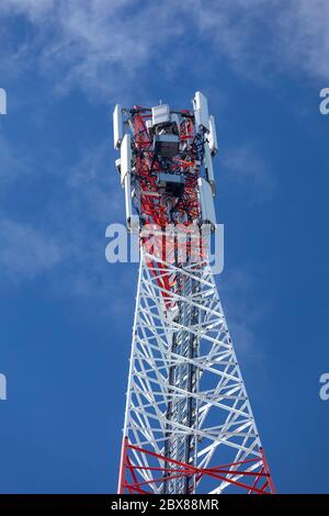 Sommet d'une tour d'antenne réseau cellulaire métallique rouge et blanc autosupport avec plusieurs antennes contre le ciel bleu , Finlande Banque D'Images