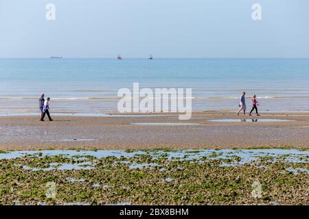 Worthing, Sussex, Royaume-Uni; 25 mai 2020; deux couples marchant le long de la mer. Deux bateaux de pêche et un plus grand navire peuvent être vus sur le Horizen Banque D'Images