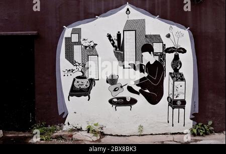 Vue générale d'un mur autour de Chinatown peint avec des œuvres d'art de rue créatives et des graphiques montrant un homme à l'intérieur de sa maison en noir et blanc. Banque D'Images