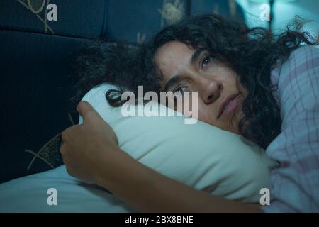 style de vie nocturne dramatique potrait de jeune triste et déprimé moyenne-orientale avec les cheveux bouclés sans sommeil dans le lit éveillé sentiment inquiet souffrant deprr Banque D'Images