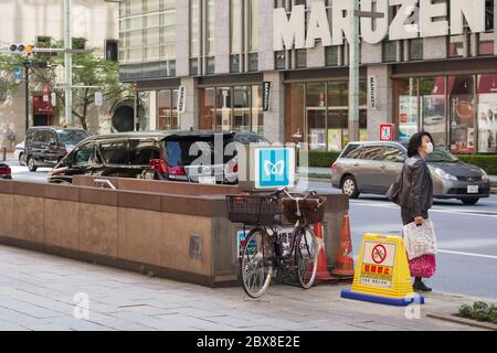 Rue Nihonbashi avec entrée de la station de métro et librairie Maruzen. En raison de l'épidémie de coronavirus, la plupart des magasins sont fermés et les gens portent des masques. Banque D'Images