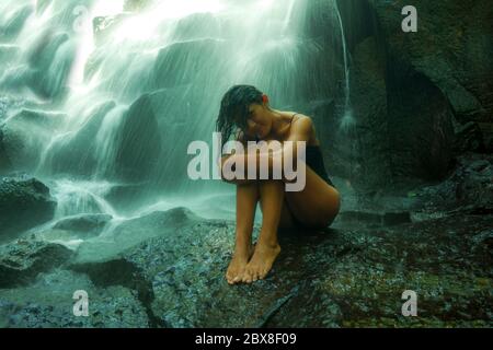 Jeune femme asiatique indonésienne attrayante et blissful submergée par la beauté de la cascade naturelle dans la jungle tropicale appréciant heureux et étonnant Banque D'Images