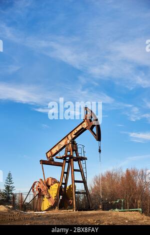 Photo verticale du cric de pompe contre le ciel bleu sur beau jour ensoleillé, situé dans la région montagneuse, espace de copie. Concept de l'industrie pétrolière Banque D'Images