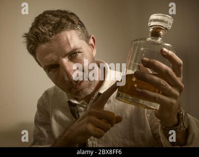 portrait dramatique de 30s à 40s homme dans le cou de perdre boire de l'alcool désespéré et gaspillé tenant le flacon de whisky se sentant ivre et déprimé boire Banque D'Images