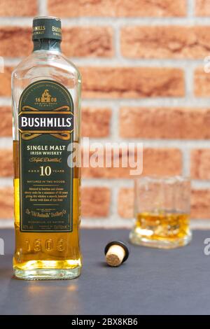 Une bouteille de whisky single malt Bushmills avec un verre sur fond de clinker Banque D'Images