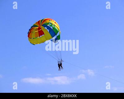 Aventure en parachute ascensionnel sur la plage. Attraction touristique. Parachute dans un ciel bleu Banque D'Images