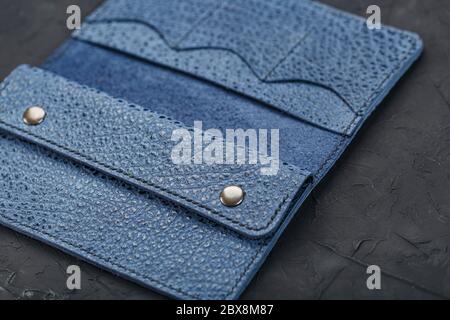 Portefeuille en cuir bleu sur fond texturé noir. Banque D'Images