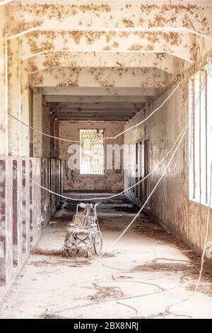 Fauteuil roulant couvert de poussière dans le couloir abandonné d'un bâtiment abandonné, espace de copie, pas de personnes Banque D'Images