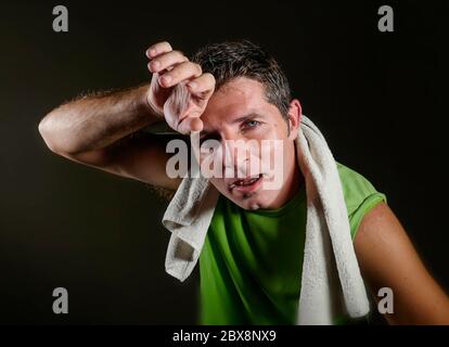jeune sportif fatigué et épuisé, sèche la sueur avec une serviette, tout sueur et respirante après un entraînement dur et un entraînement physique isolé sur le backgro sombre Banque D'Images
