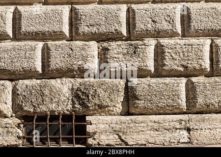 Ashlar (Bugnato en italien), fermeture d'un mur fait de gros blocs de pierres et de vieille fenêtre avec barres de sécurité en fer forgé. Trento, Italie Banque D'Images