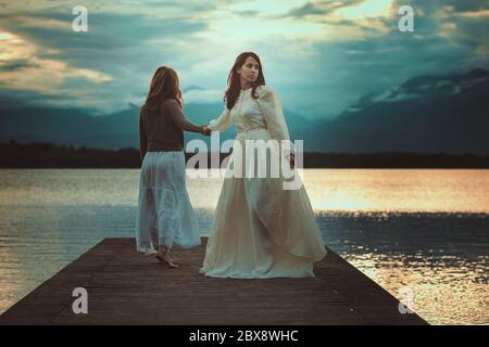 De belles femmes marchant sur le lac. Coucher de soleil surréaliste Banque D'Images
