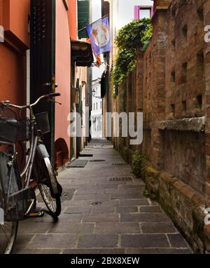 Tourisme en Vénétie et point d'intérêt parmi les ruelles étroites et les maisons maritme à Caorle port avec des vélos et des maisons colorées. Banque D'Images
