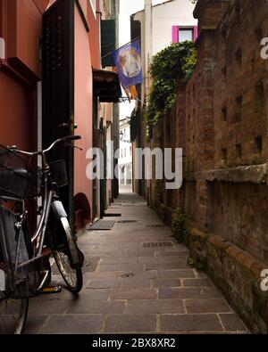 Tourisme en Vénétie et point d'intérêt parmi les ruelles étroites et les maisons maritme à Caorle port avec des vélos et des maisons colorées. Banque D'Images