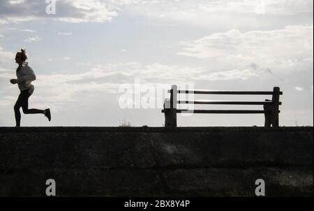 Littoral, local, femme, femme, silhouette, courir, courir, le long, promenade, dans, Borth. Prendre,elle,permis,exercice,quotidien,sur,une,journée,ensoleillée,sur,la,côte,côtière,littoral,vacances,station,village,de,Borth,nord,de,Aberystwyth,Ceredigion,Mid,West,Wales,Welsh,UK,GB,Britain,British,UK,.actuellement le pays de Galles est fermé aux touristes, pendant,Covid 19,coronavirus,calme,les paysages,non,les touristes,la pandémie,les touristes,les touristes,les touristes,les touristes,les touristes,les touristes, Banque D'Images