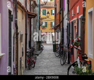 Caorle: Tourisme en Vénétie et point d'intérêt parmi les ruelles étroites et les maisons maritme à Caorle port avec des vélos et des maisons colorées. Banque D'Images