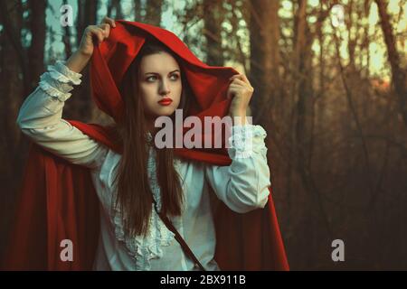 Portrait aux tons sombres de la petite cagoule rouge dans les bois Banque D'Images