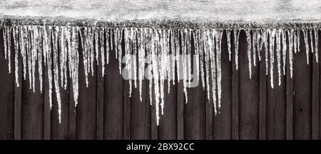 Rangée de glaçons accrochée sur le toit. Scène rurale d'hiver. Banque D'Images