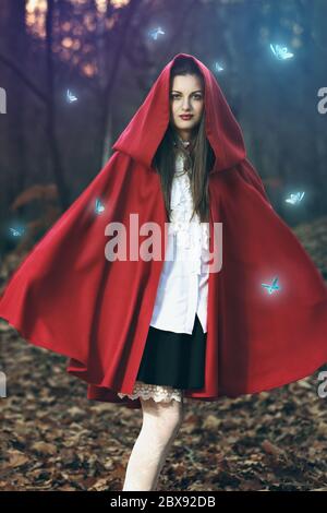Magnifique portrait de fantaisie d'une fille vêtue de manteau rouge parmi les papillons magiques Banque D'Images