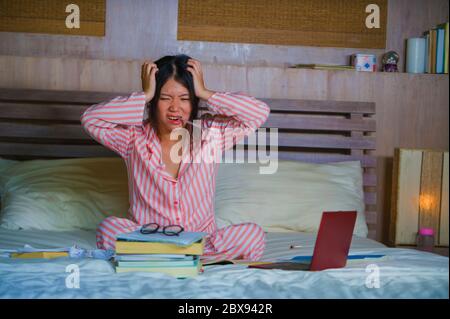 Jeune femme asiatique, frustrée et fatiguée, étudiante à l'université japonaise, se sentant submergée et stressée, préparant l'examen avec ordinateur portable dans St Banque D'Images