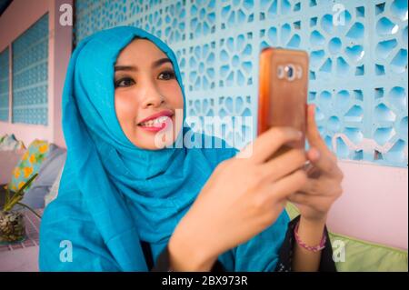 portrait de style de vie en plein air de jeune femme heureuse et belle dans le foulard hijab musulman utilisant l'application internet de médias sociaux sur le téléphone mobile envoyer du texte Banque D'Images