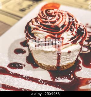 Cheesecake avec sauce aux fruits de la forêt, avec une saupoudrage de sucre. Photo de style rétro. Banque D'Images