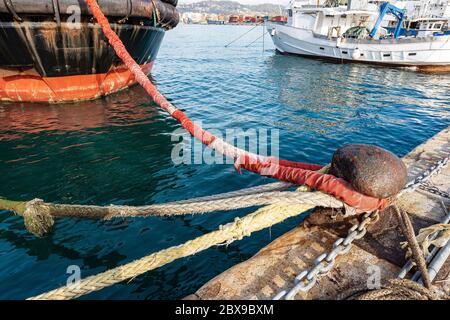 Bateaux amarrés dans le port. Grand bollard rouillé avec des colles, des chaînes et des cordes sur le quai du port. La Spezia, Ligurie, Italie, Europe Banque D'Images