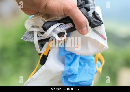 Main humaine avec un masque médical de déchets sales et des gants déchets, matériel de maladie de coronavirus Banque D'Images