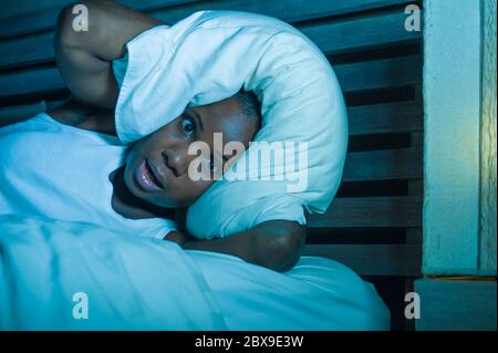 Portrait de nuit de style de vie de jeune femme africaine noire américaine désespéré et stressée couché sur le lit contrarié essayant de dormir souffrant de maux de tête et hangov Banque D'Images