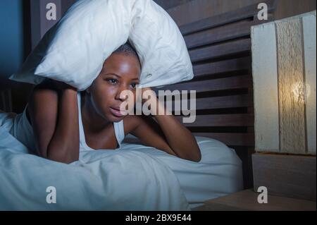 Portrait de nuit de style de vie de jeune femme africaine noire américaine désespéré et stressée couché sur le lit contrarié essayant de dormir souffrant de maux de tête et hangov Banque D'Images