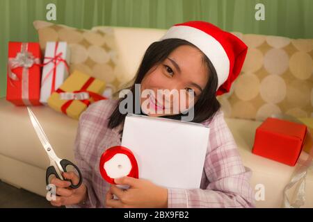 Noël vacances style de vie portrait de jeune belle et heureuse femme asiatique coréenne dans le chapeau de Santa excitée emballage xmas présente emballage cadeaux avec p Banque D'Images