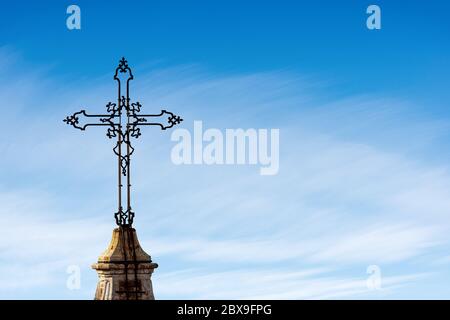 Croix chrétienne en fer forgé sur un ciel bleu avec des nuages. Cathédrale métropolitaine de San Pietro (910 - XVIII siècle), Bologne, Émilie-Romagne, Italie Banque D'Images