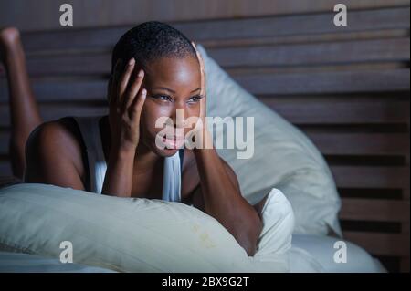 Jeune triste et déprimé noir afro américaine femme dans le lit sans sommeil tard la nuit se sentant désespéré regardant inquiet et anxieux souffrant dépression probl Banque D'Images