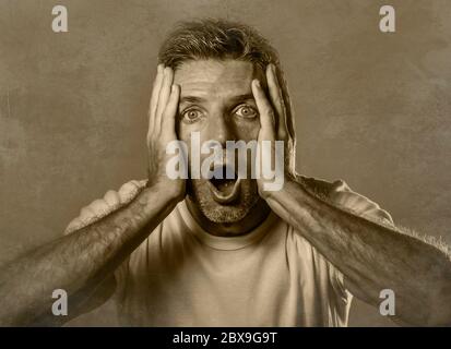 portrait noir et blanc d'homme attrayant en état de choc et surpris avec les mains sur le visage alarmé avec la bouche et les yeux grand ouverts dans l'incrédulité et surprise e Banque D'Images