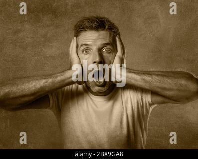 portrait noir et blanc d'homme attrayant en état de choc et surpris avec les mains sur le visage alarmé avec la bouche et les yeux grand ouverts dans l'incrédulité et surprise e Banque D'Images