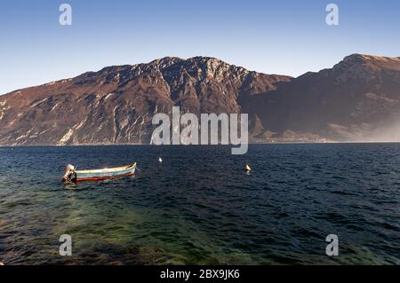 Lac de Garde avec un petit bateau et le Monte Baldo, chaîne de montagnes des Alpes vues depuis le village de Limone sul Garda. Lombardie et Vénétie, Italie. Banque D'Images