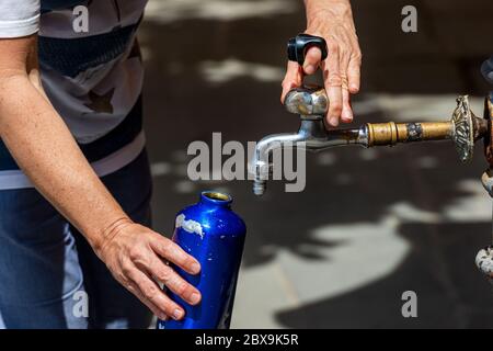 Gros plan d'une main de femme tout en remplissant une bouteille d'eau d'un robinet lors d'une chaude journée d'été. Italie, Europe Banque D'Images