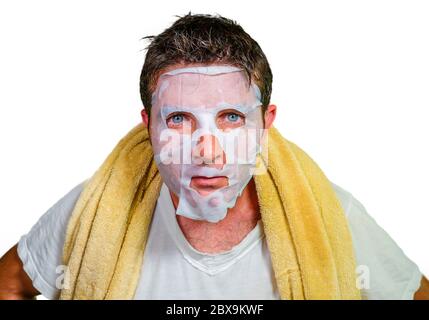 style de vie isolé portrait de fond de jeune étrange et drôle homme à la maison essayant d'utiliser le papier masque facial de nettoyage appliquant le traitement de beauté anti vieillissement Banque D'Images